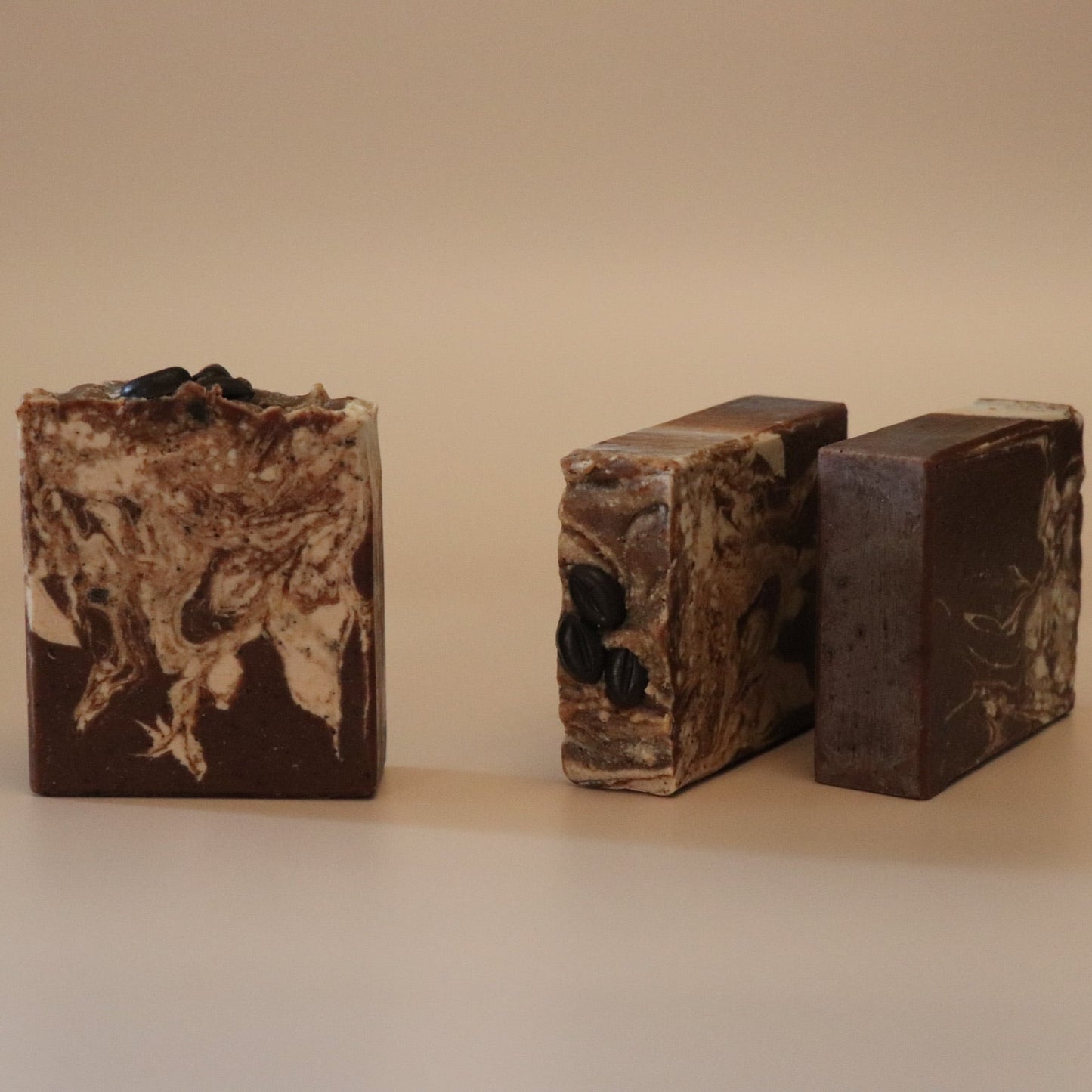 Three bars of brown soap with a marbled pattern on a beige background