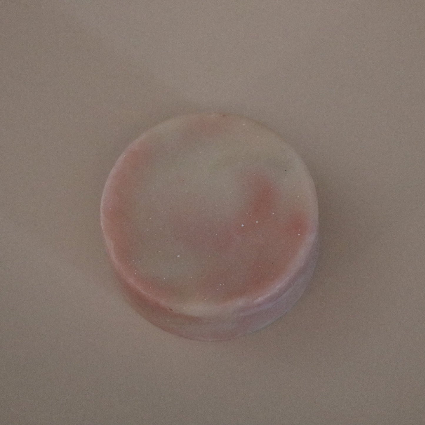 Round pink and white soap on a beige background