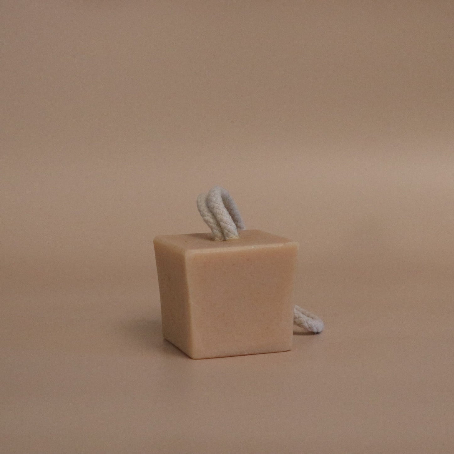 Cube beige soap with a rope on a beige background