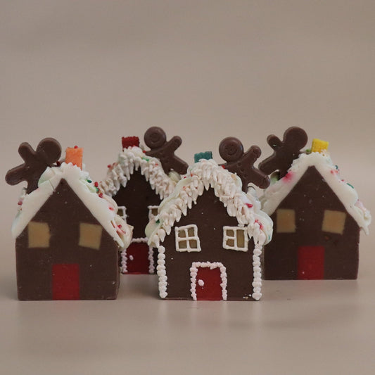 Four gingerbread house artisan soaps with decorative elements on a beige background