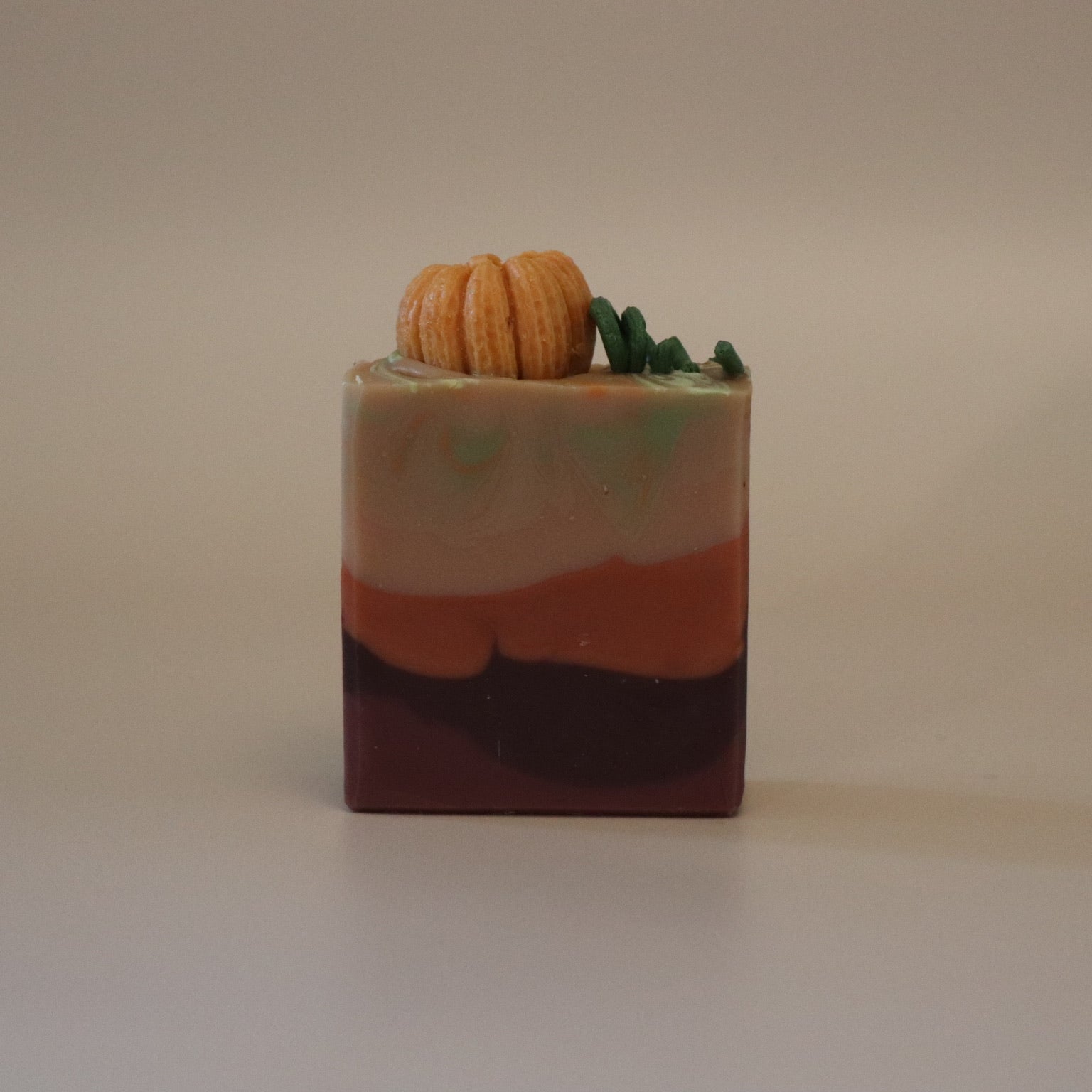 Colorful soap bar with a small pumpkin decoration on it and a beige background