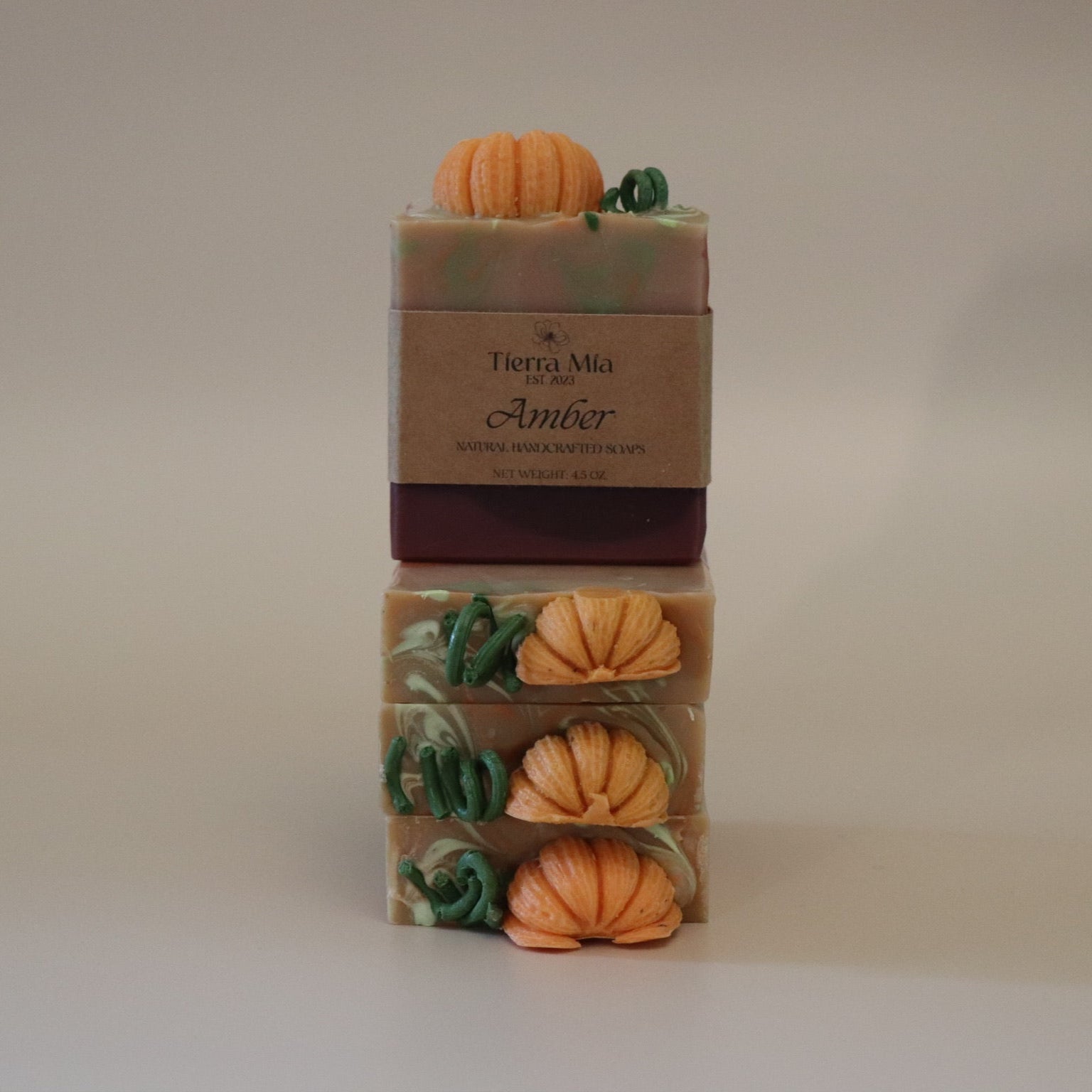 Four stacked soap bars with pumpkin decorations on a neutral background