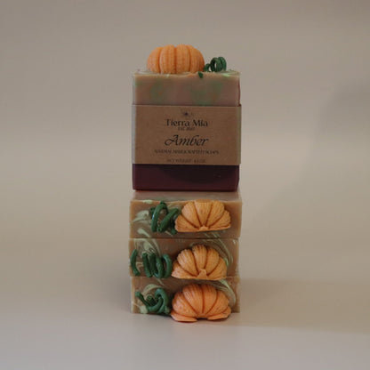 Four stacked soap bars with pumpkin decorations on a neutral background