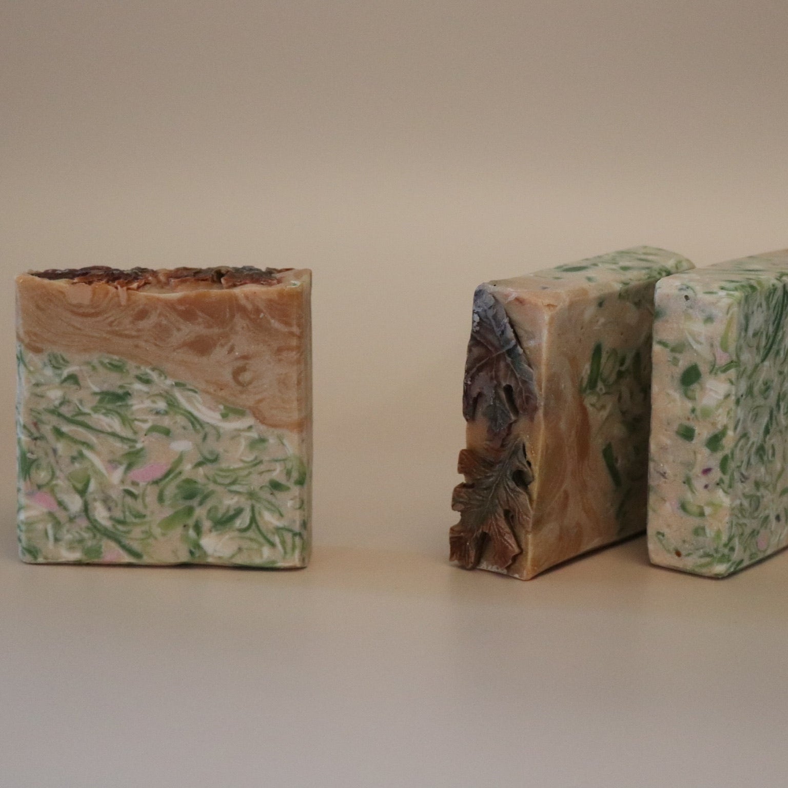 Three bars of soap with natural, textured surfaces on a plain background