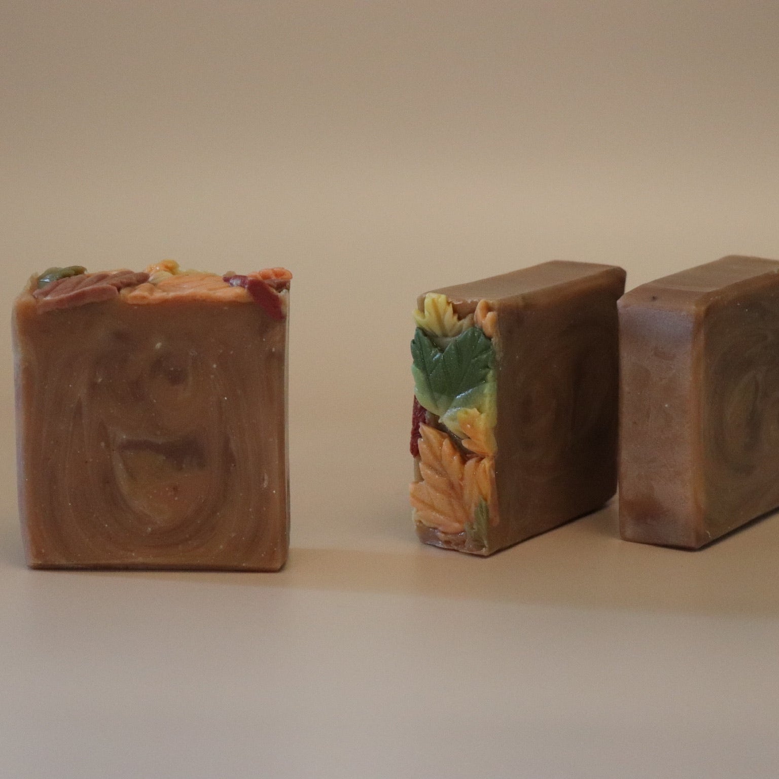 Three bars of soap with decorative toppings on a beige background