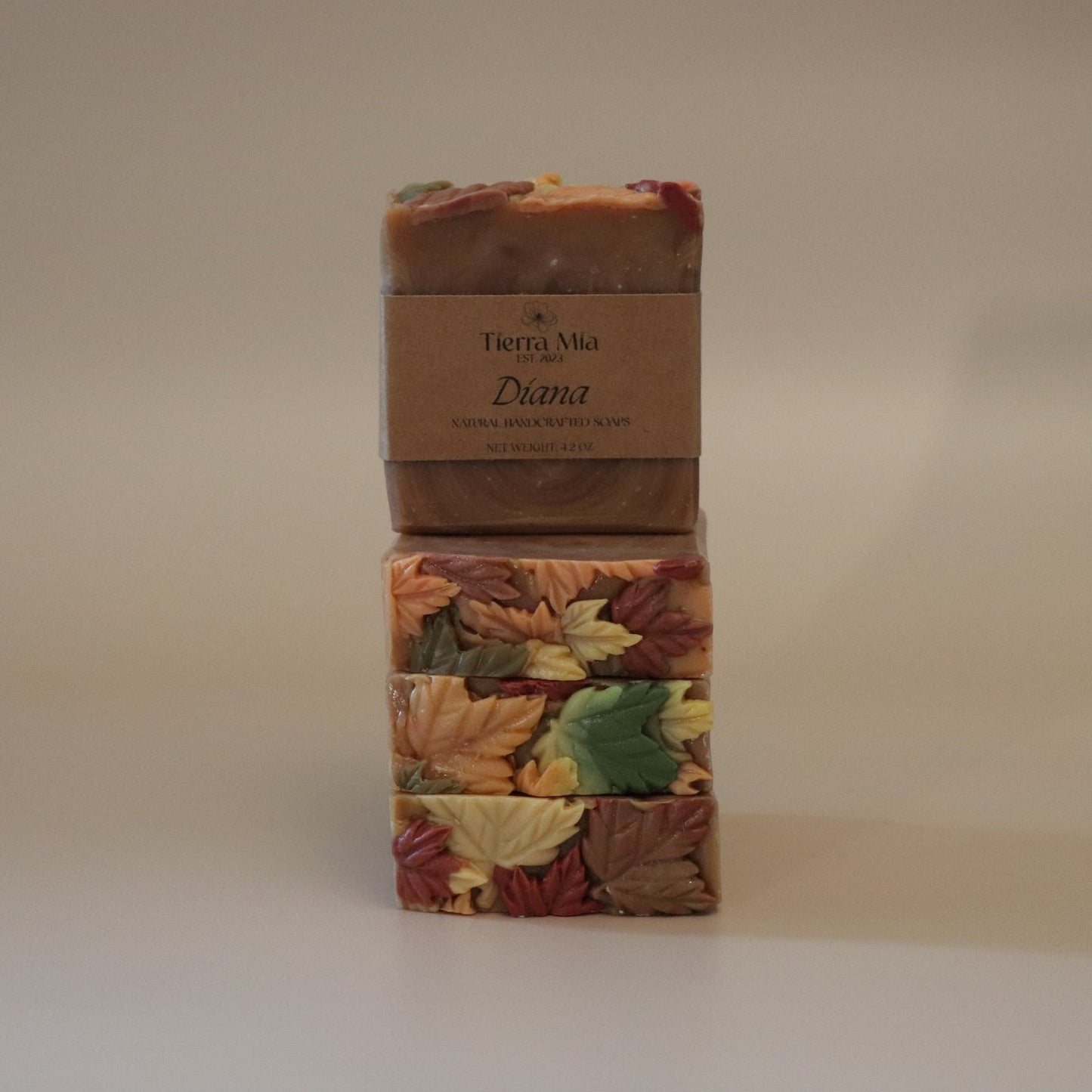 Four soap bars with autumn leaf design and a brown label on a beige background