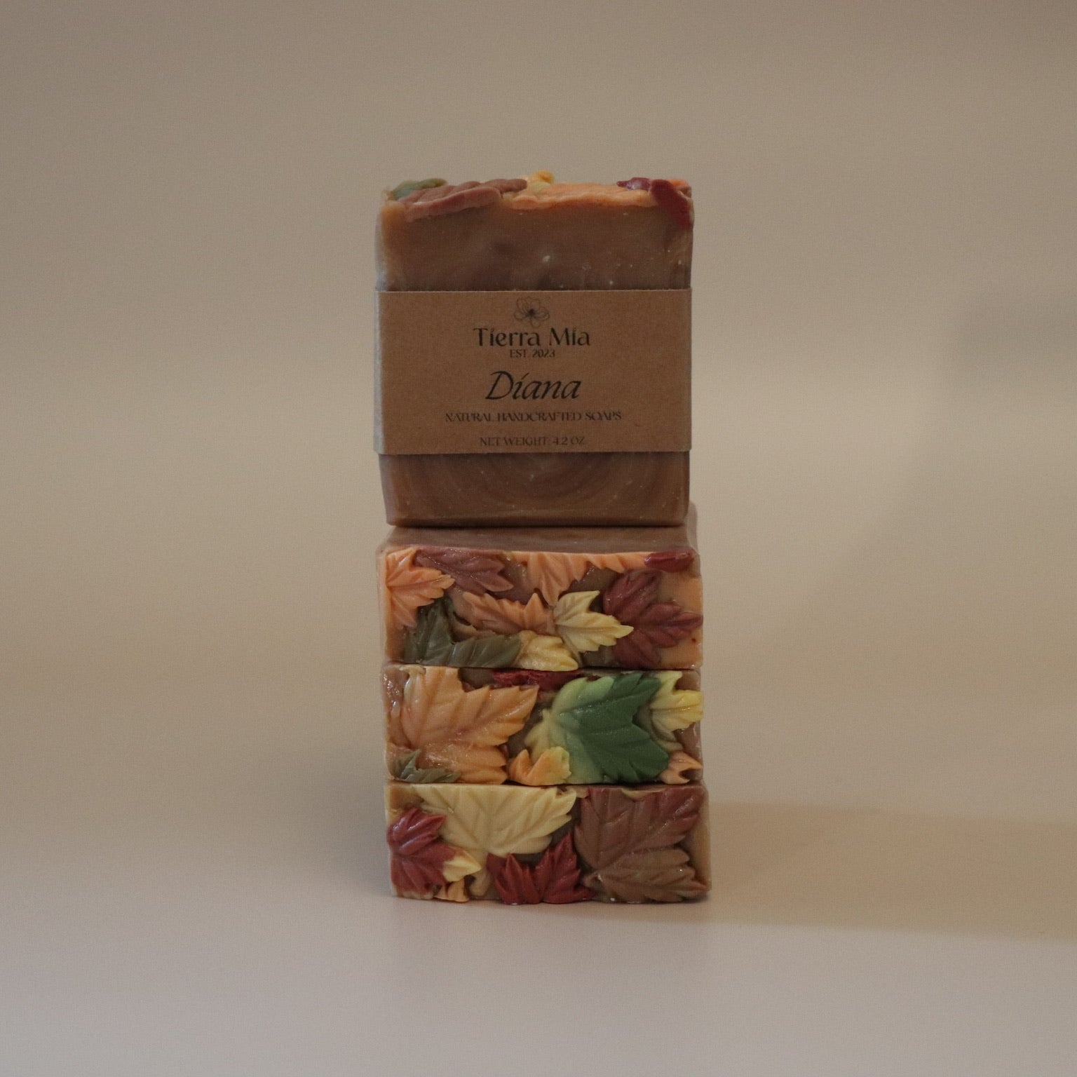 Four soap bars with autumn leaf design and a brown label on a beige background