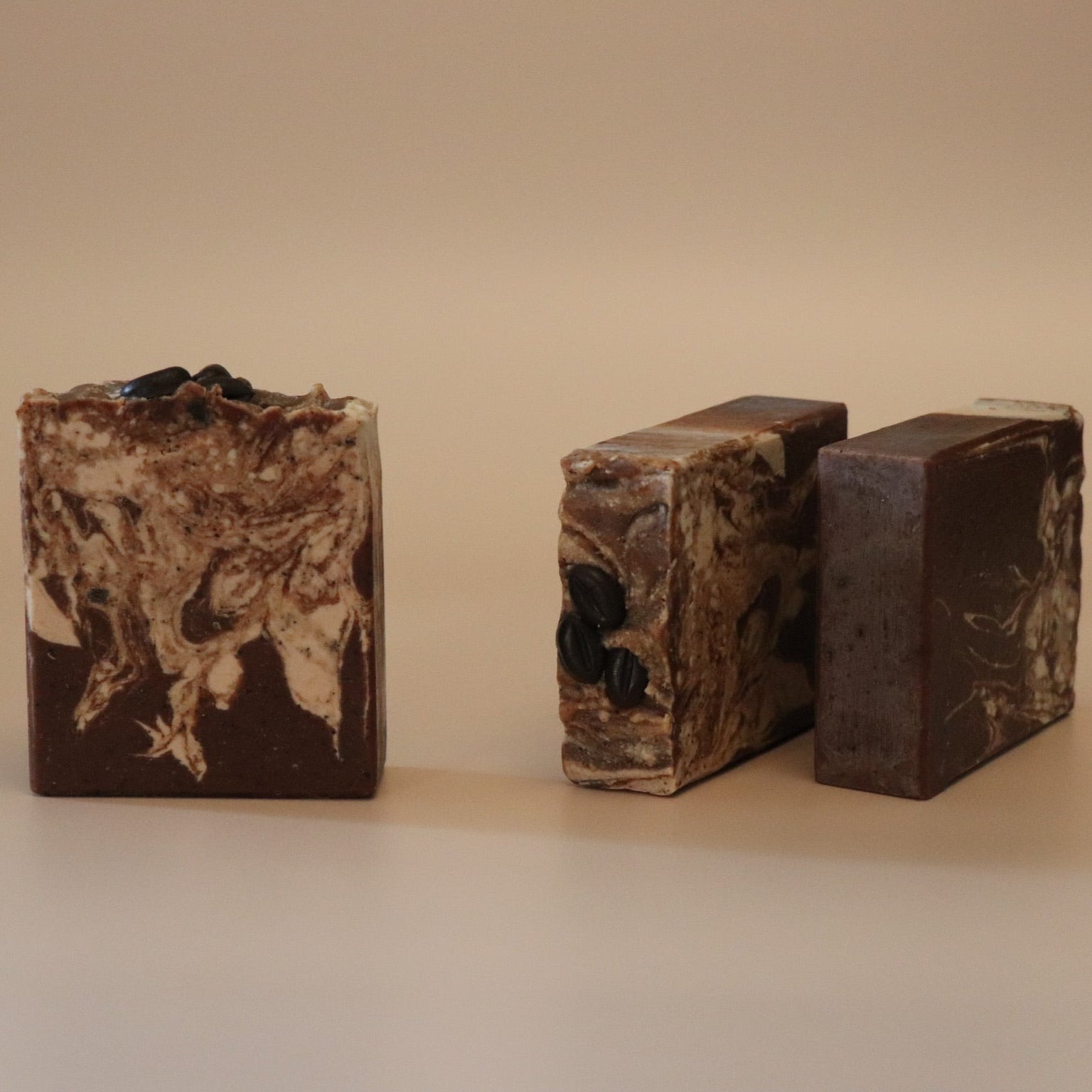Three bars of brown soap with a marbled pattern on a beige background