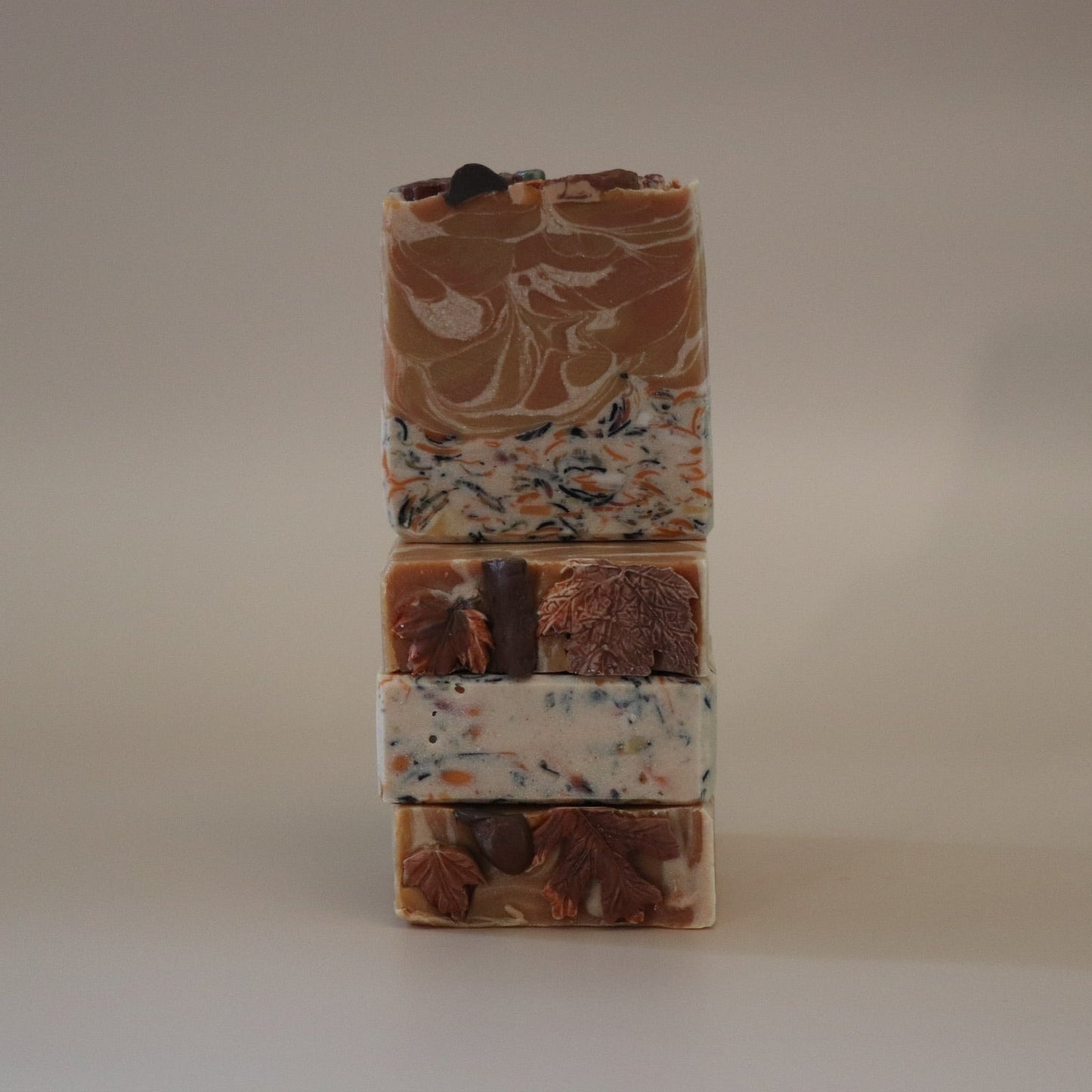 Stack of three handmade soap bars with different patterns on a beige background
