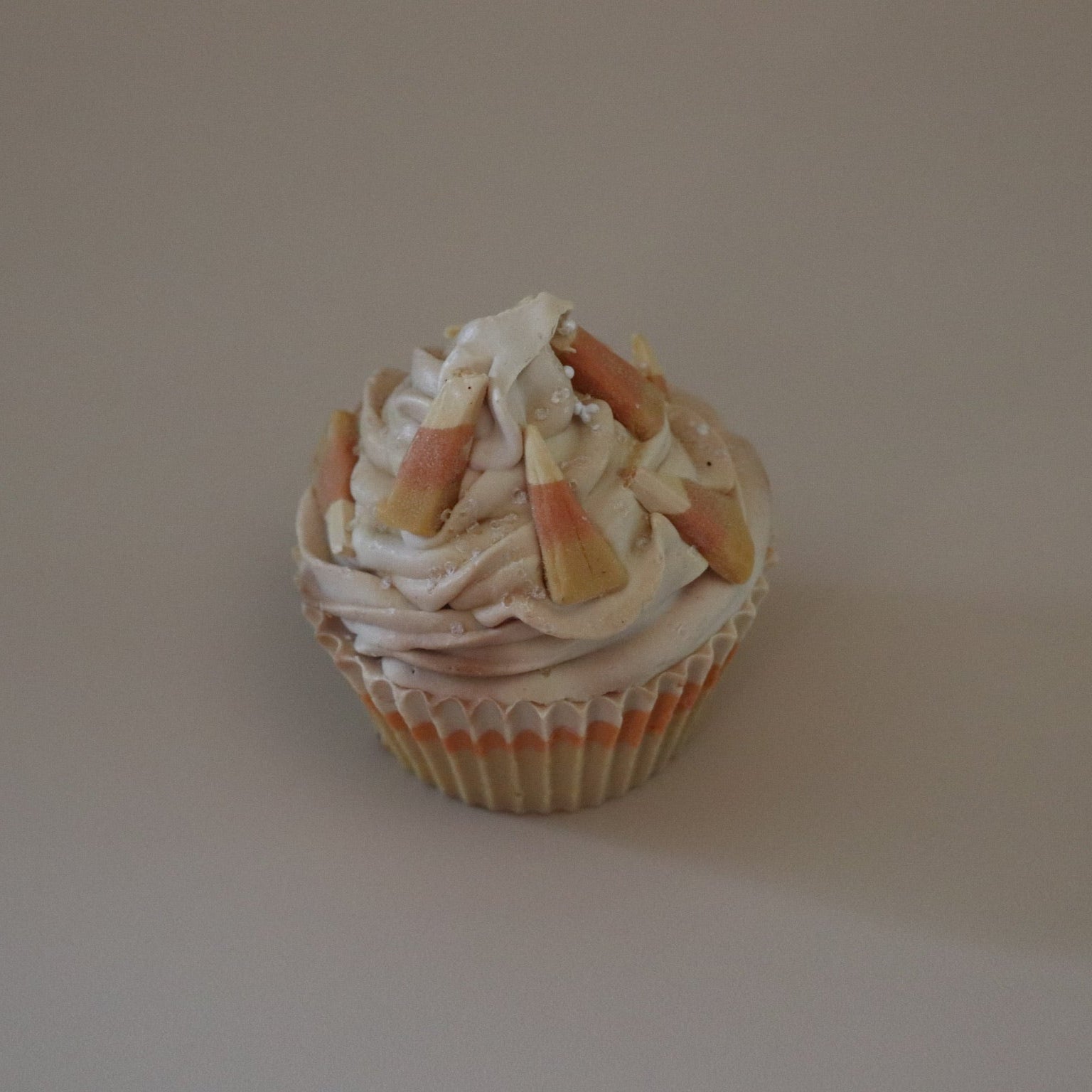 Cupcake soap bar with white frosting and candy pieces on a plain background