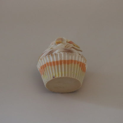 Cupcake soap bar with white frosting and a colorful paper liner on a plain background