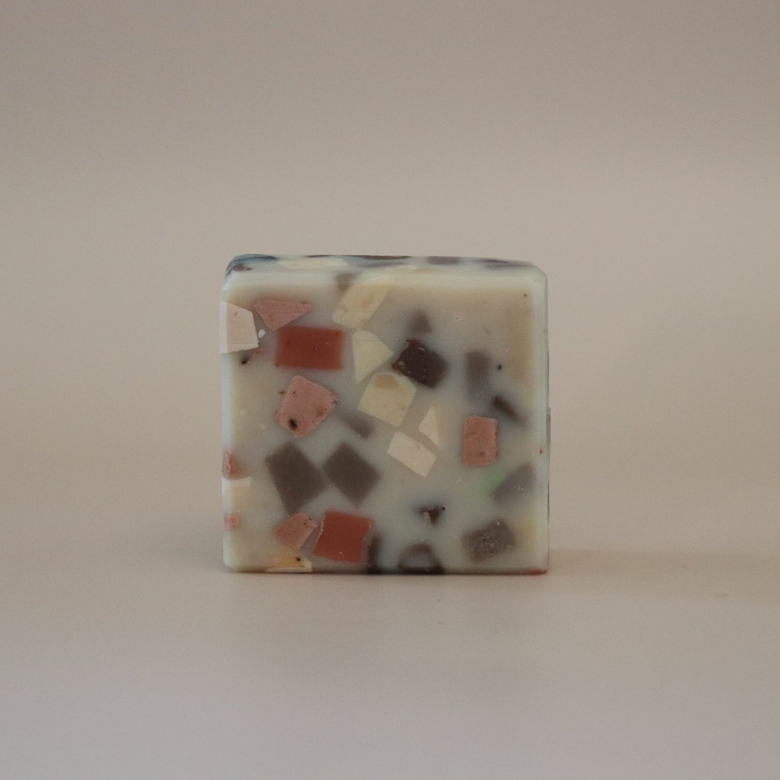Square piece of soap with multicolored mosaic pattern on a beige background