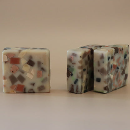 Two terrazzo-patterned cube soaps on a beige background