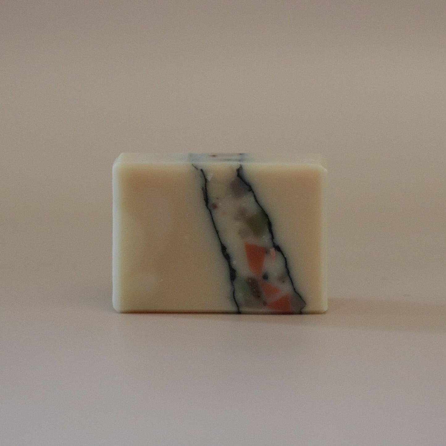 Square bar of soap with marbled design on a beige background