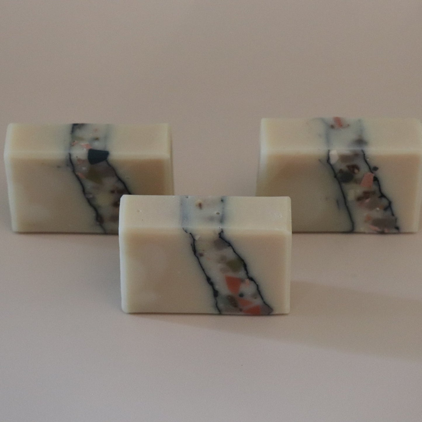Three square bars of soap with multicolored stripes on a white background