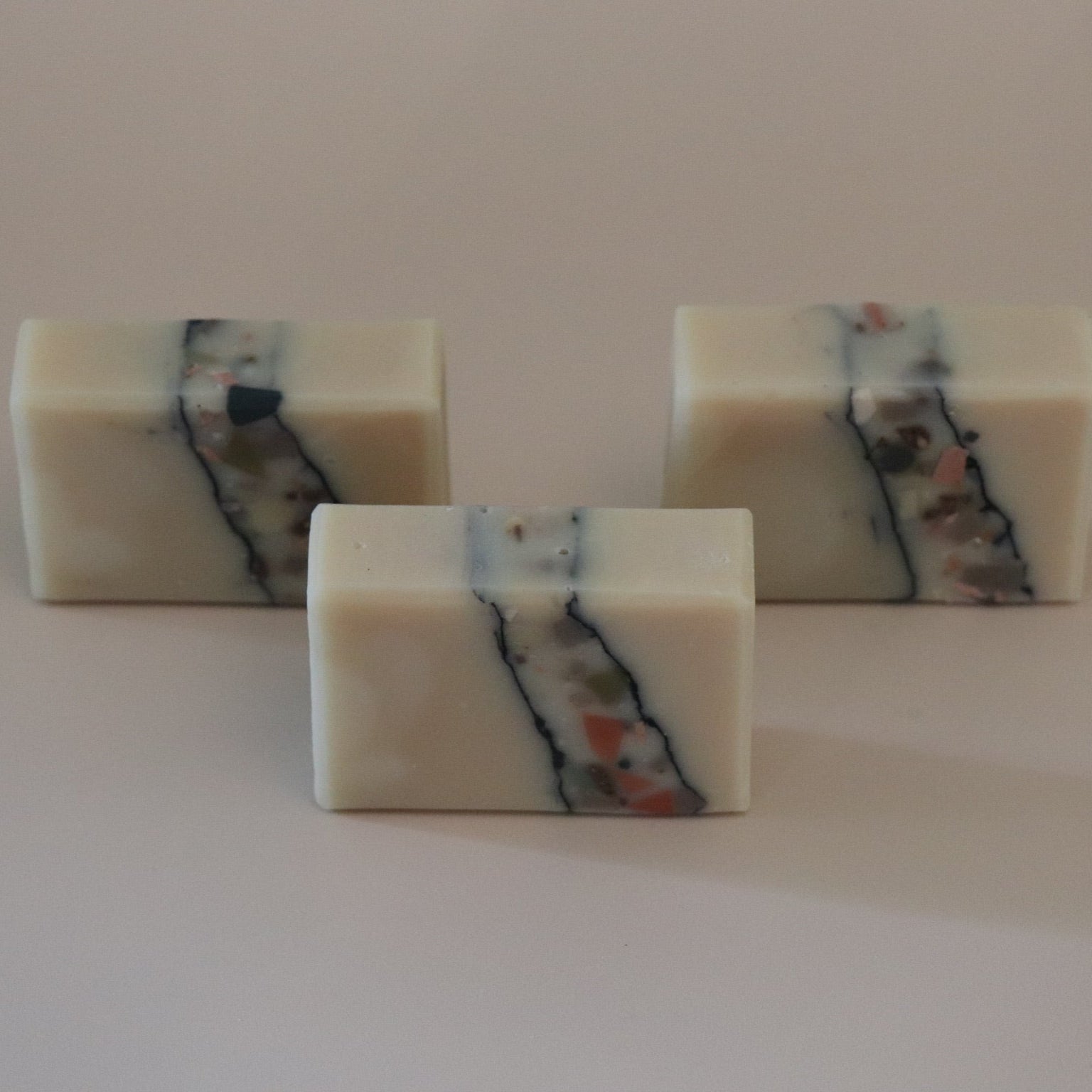 Three square bars of soap with multicolored stripes on a white background