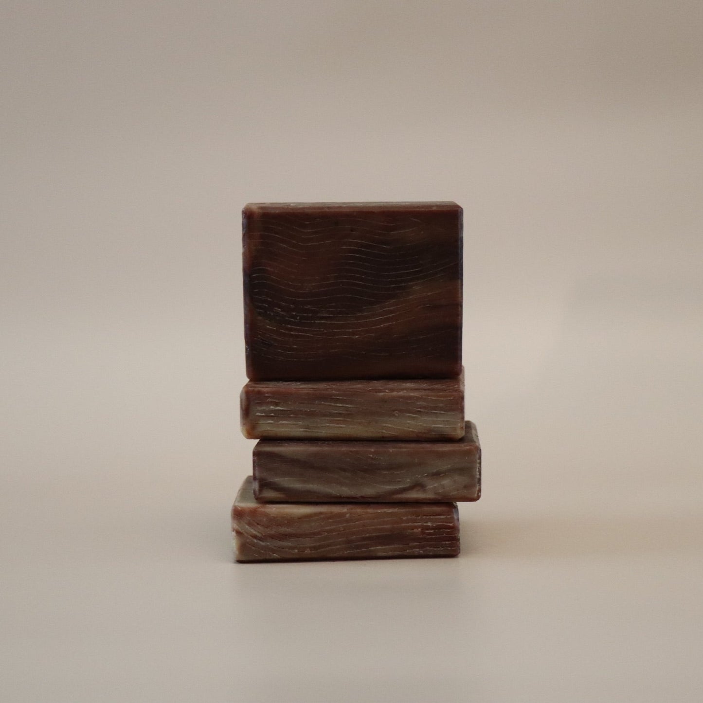 Stack of three wooden blocks soap bars on a beige background