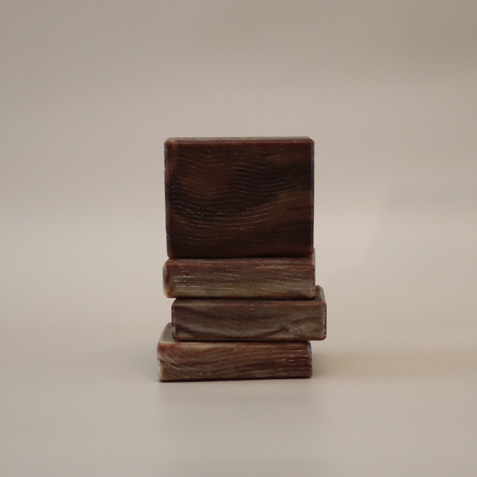 Stack of three wooden blocks soap bars on a beige background