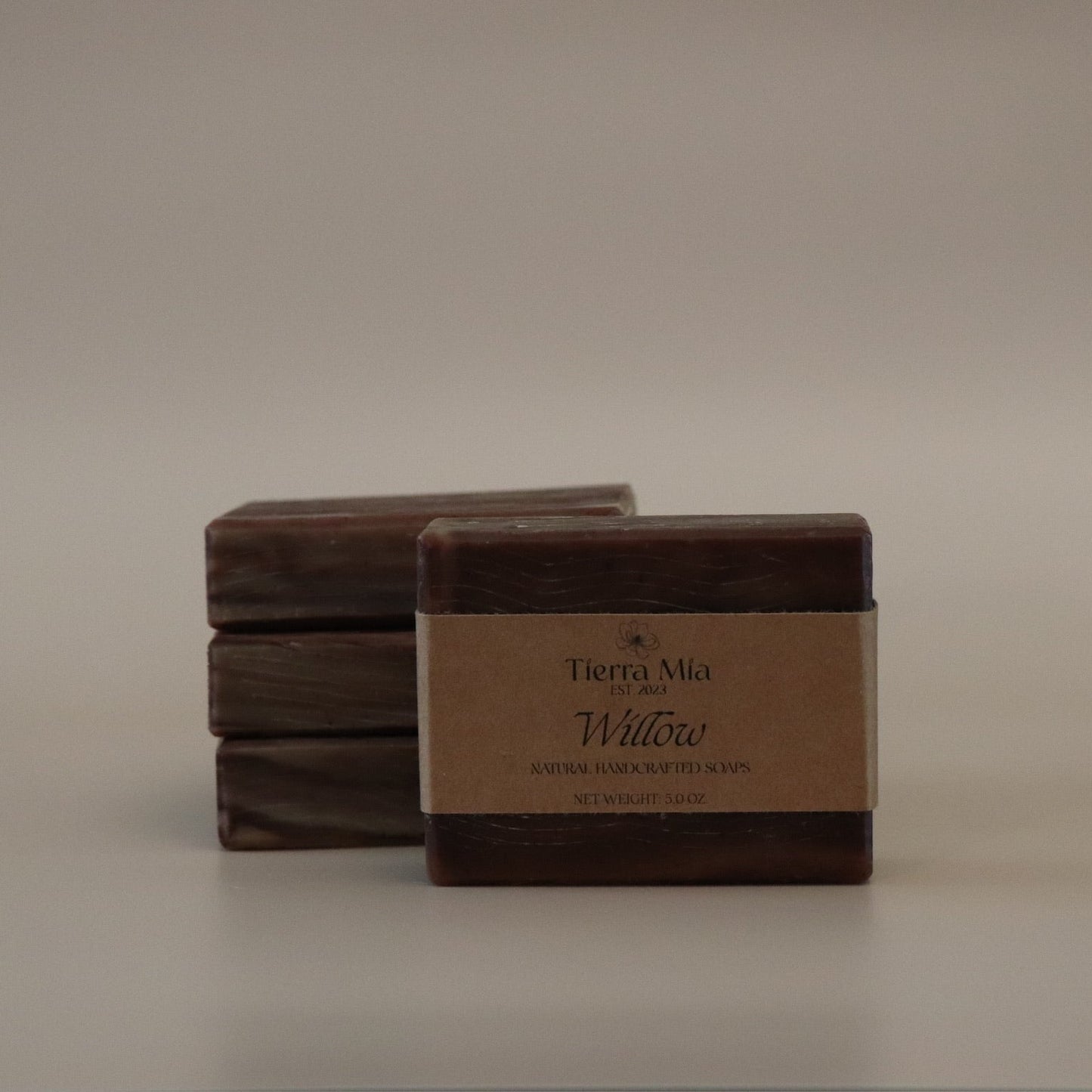 Four brown soap bars with a label on a beige background