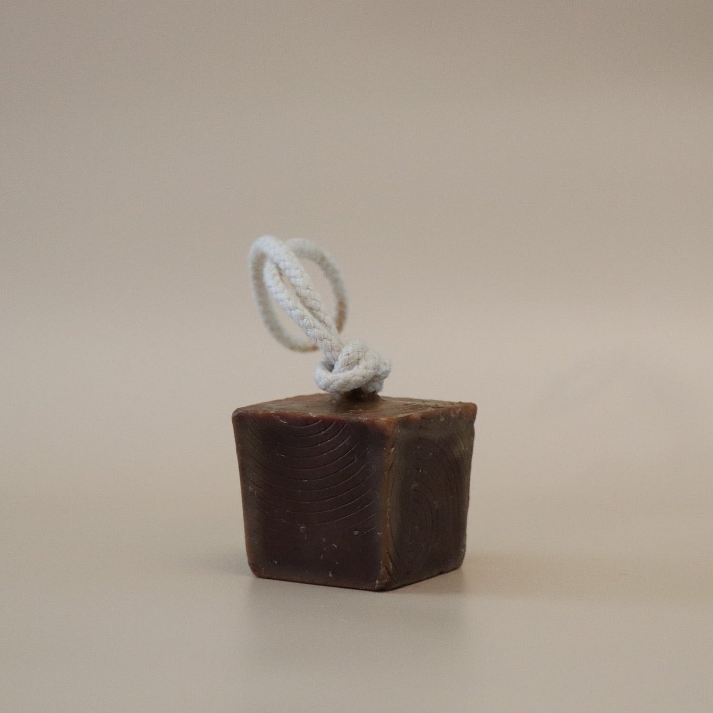 Brown Cube soap with a white rope on a beige background