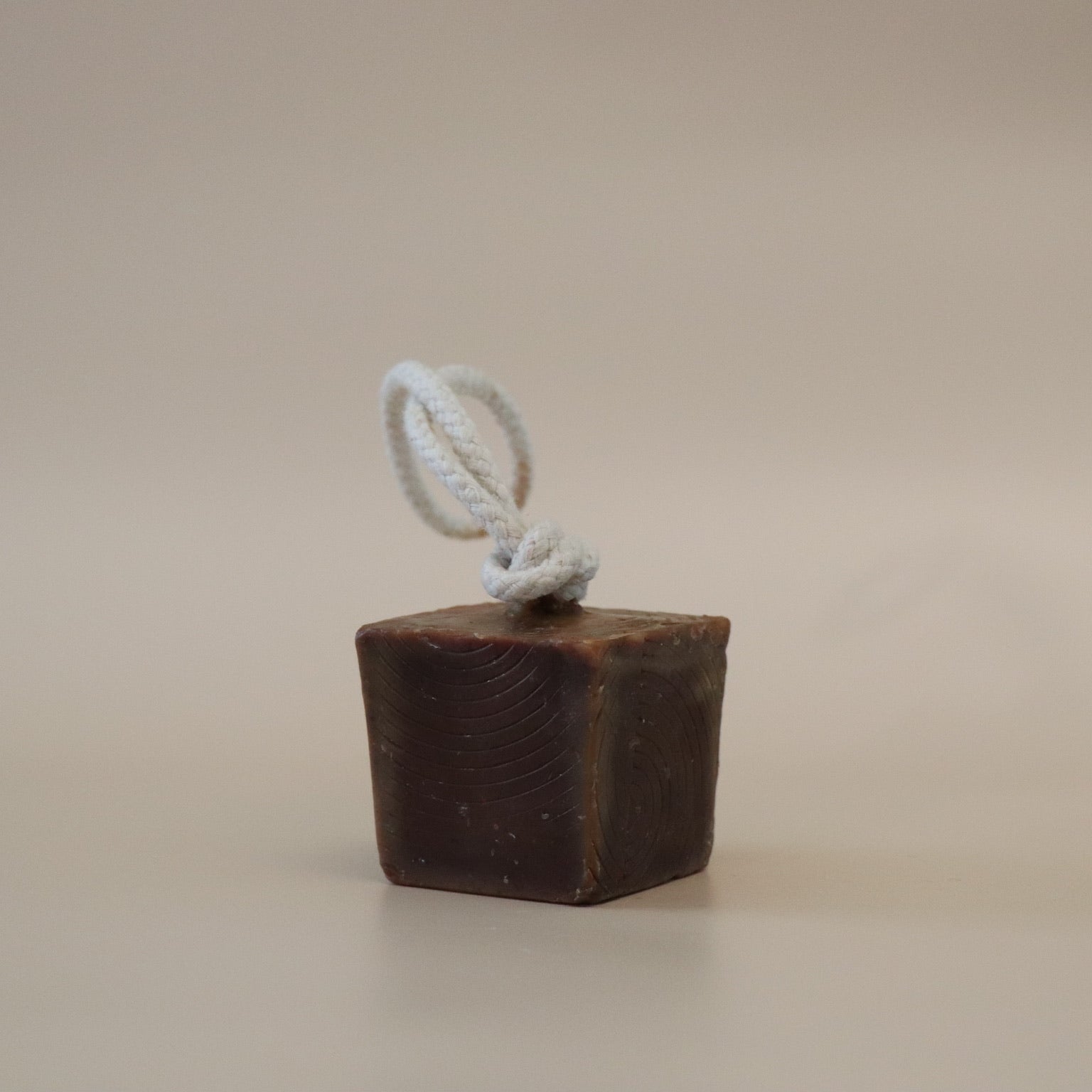 Brown Cube soap with a white rope on a beige background