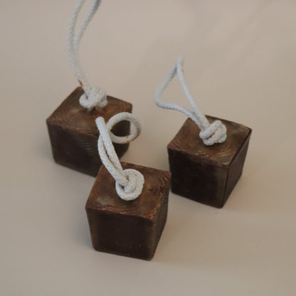 Three wooden block soap bars with ropes tied to them on a beige background