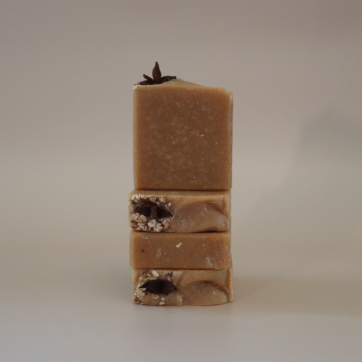 Stack of three brown soap bars with visible textures on a beige background