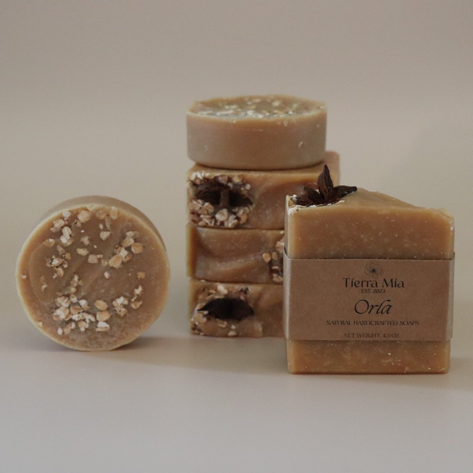 Three bars of soap with visible textures and a box labeled 'Tierra Mia' on a beige background