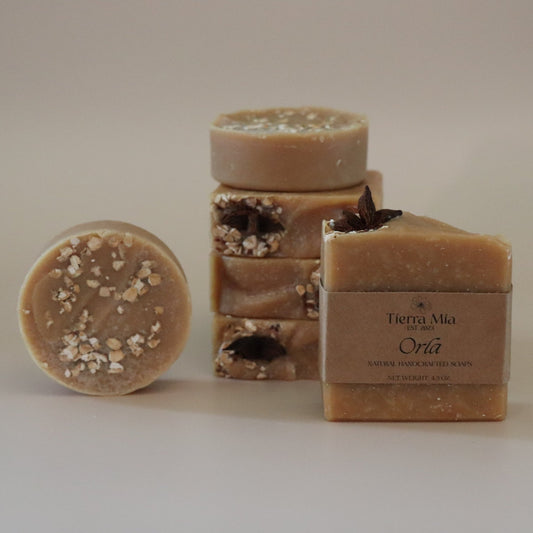 Three bars of soap with visible textures and a box labeled 'Tierra Mia' on a beige background