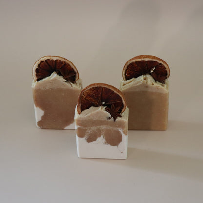 Three layered soap bars with natural elements on a neutral background