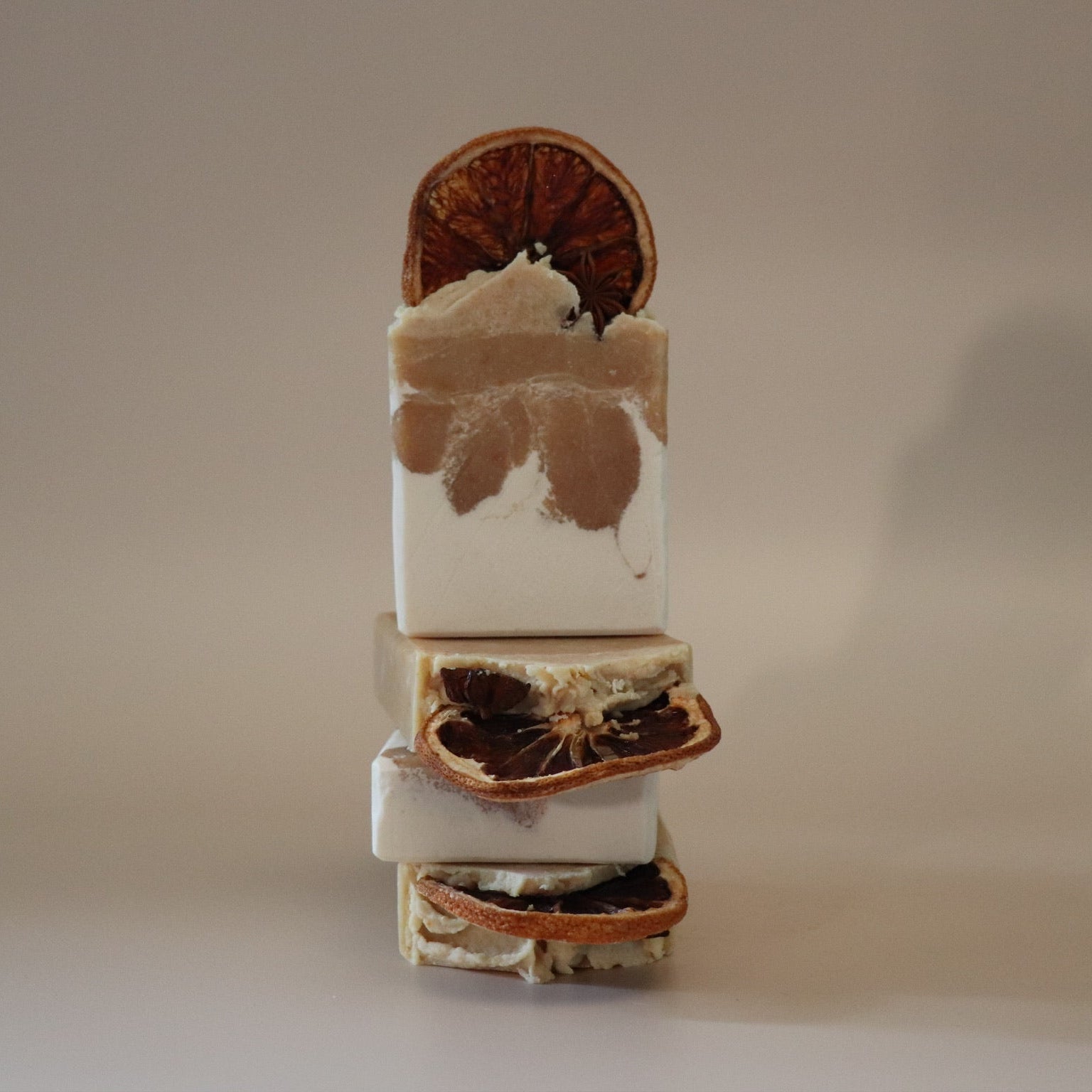 Stack of layered soap bars with natural elements on a neutral background