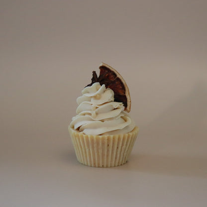 Cupcake with white frosting and a chocolate piece on a beige background