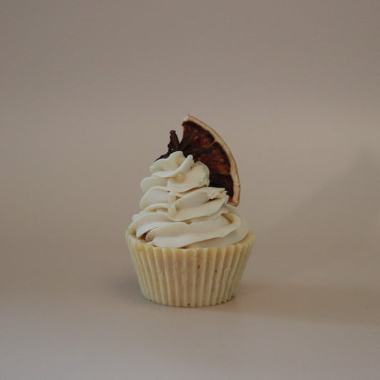 Cupcake with white frosting and a chocolate piece on a beige background