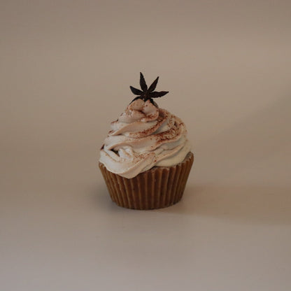 Cupcake with white frosting and a star-shaped decoration on a beige background