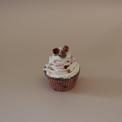 Cupcake with white frosting and red berries on a beige background