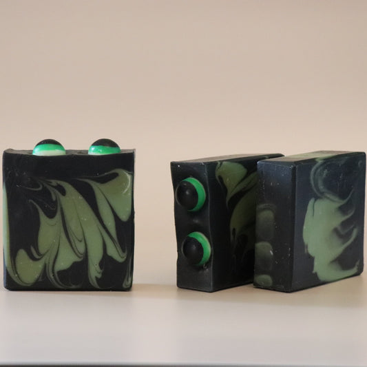 Three green and black marbled soap bars on a beige background