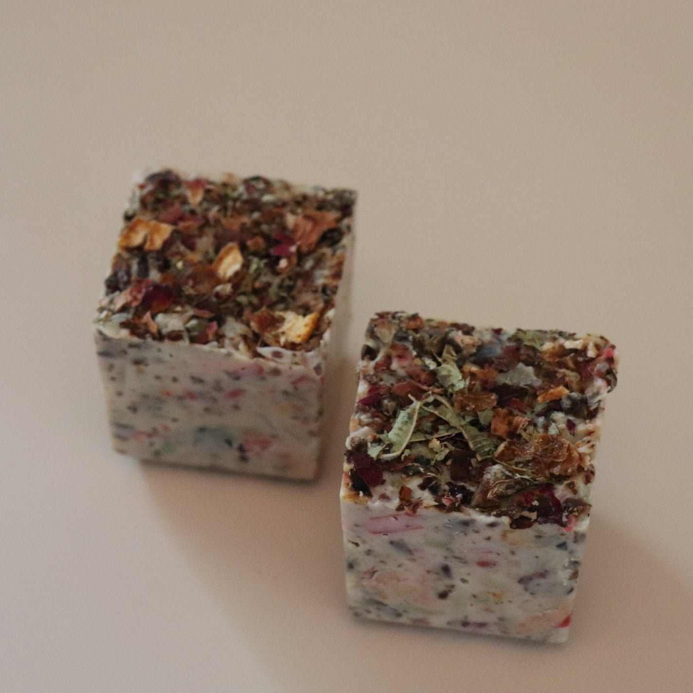 Two square-shaped soaps seed blocks on a plain background