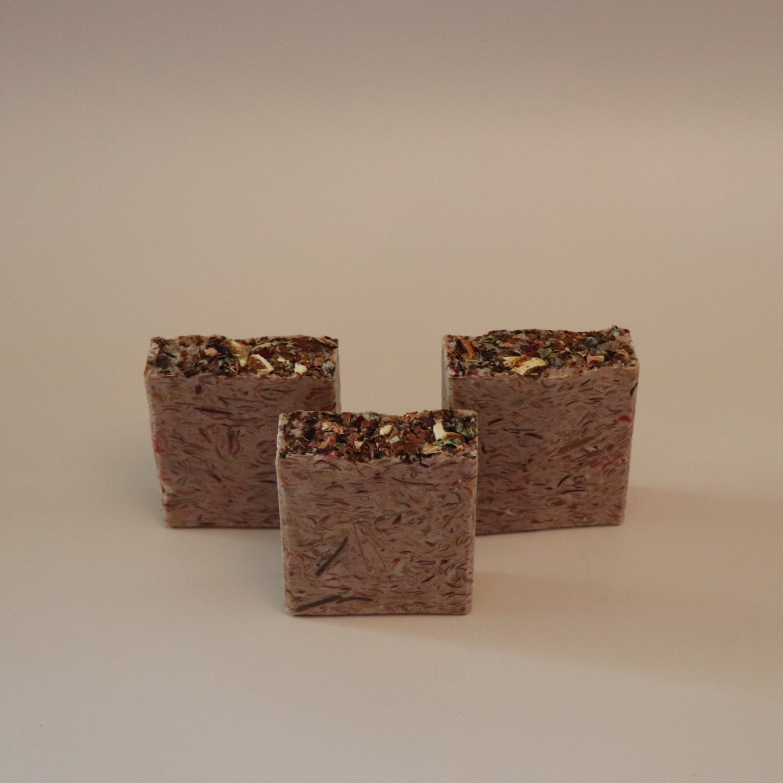 Three square brown soap bars on a beige background
