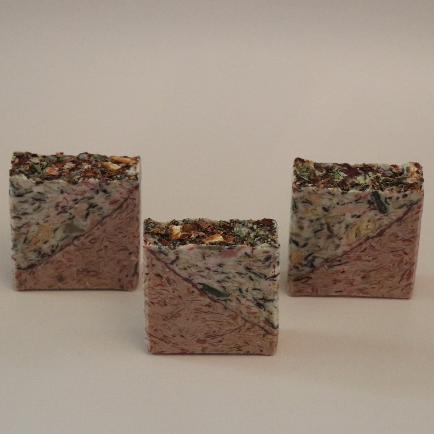 Three square, textured soap bars on a plain background
