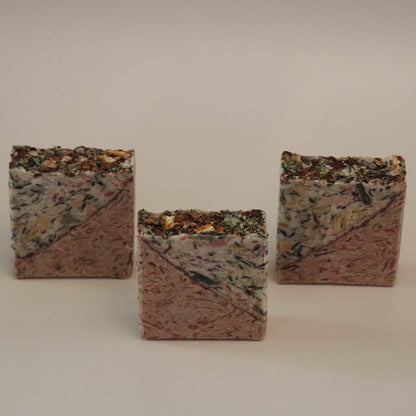 Three square, textured soap bars on a plain background