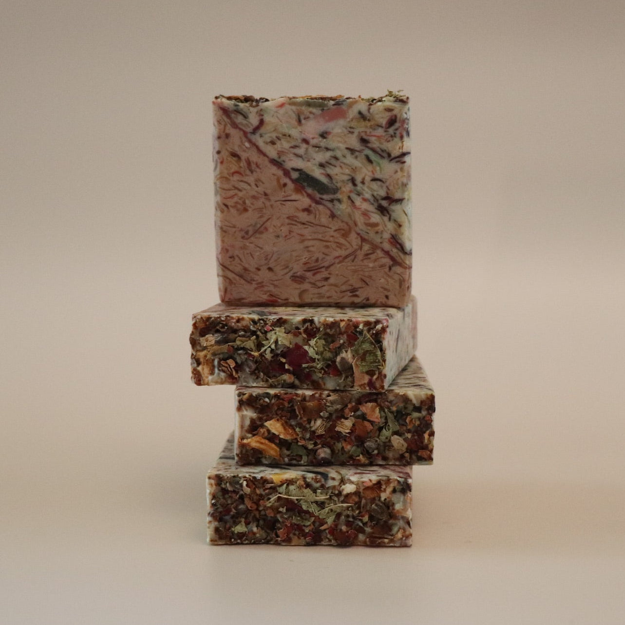 Stack of three rectangular, multicolored soap bars on a beige background