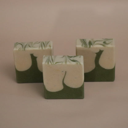 Three green and white soap bars with leaf pattern on a beige background