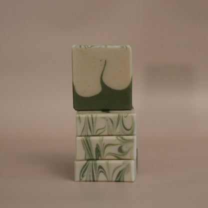 Stack of green soap bars with leaf patterns on a beige background
