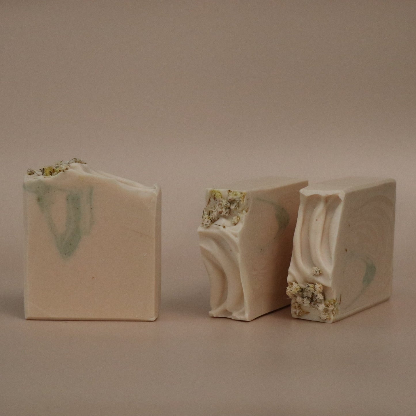 Three bars of soap with a marbled design on a beige background