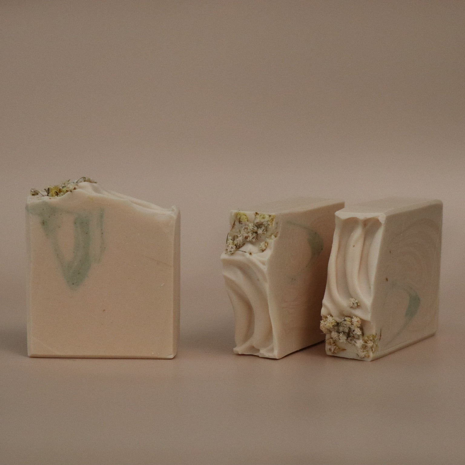 Three bars of soap with a marbled design on a beige background