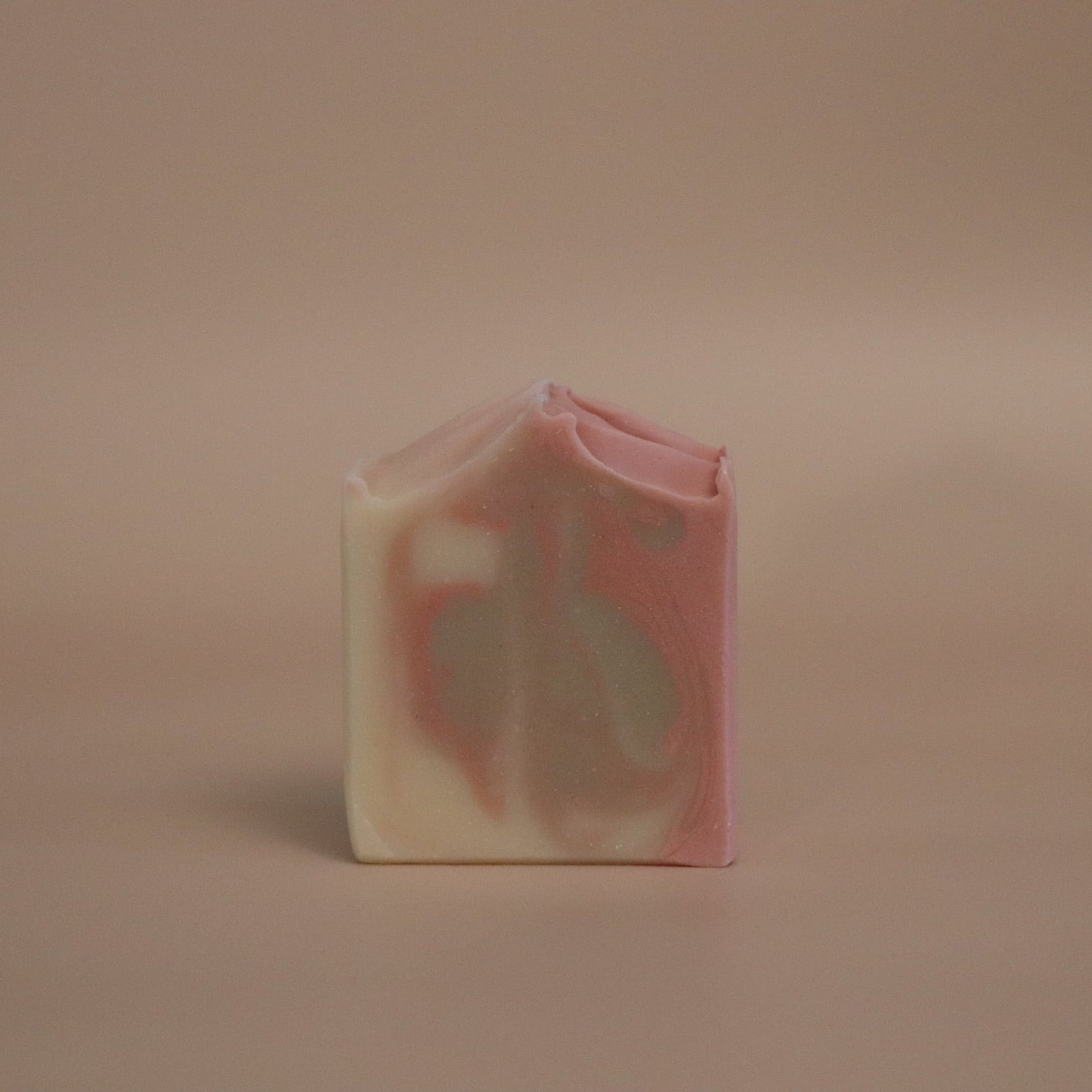 Bar of soap with pink, brown, and white marbled pattern on a beige background