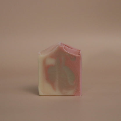 Bar of soap with pink, brown, and white marbled pattern on a beige background