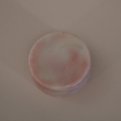 Round pink and white soap on a beige background