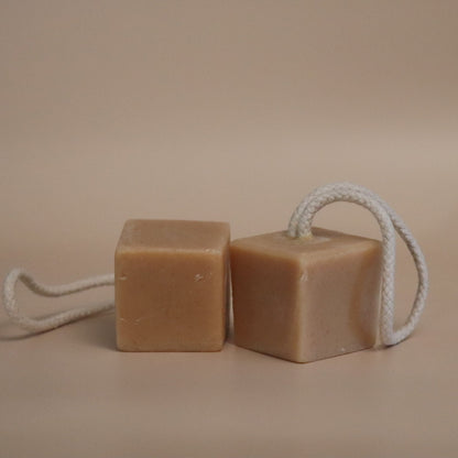 Two square bars of soap on a rope against a beige background
