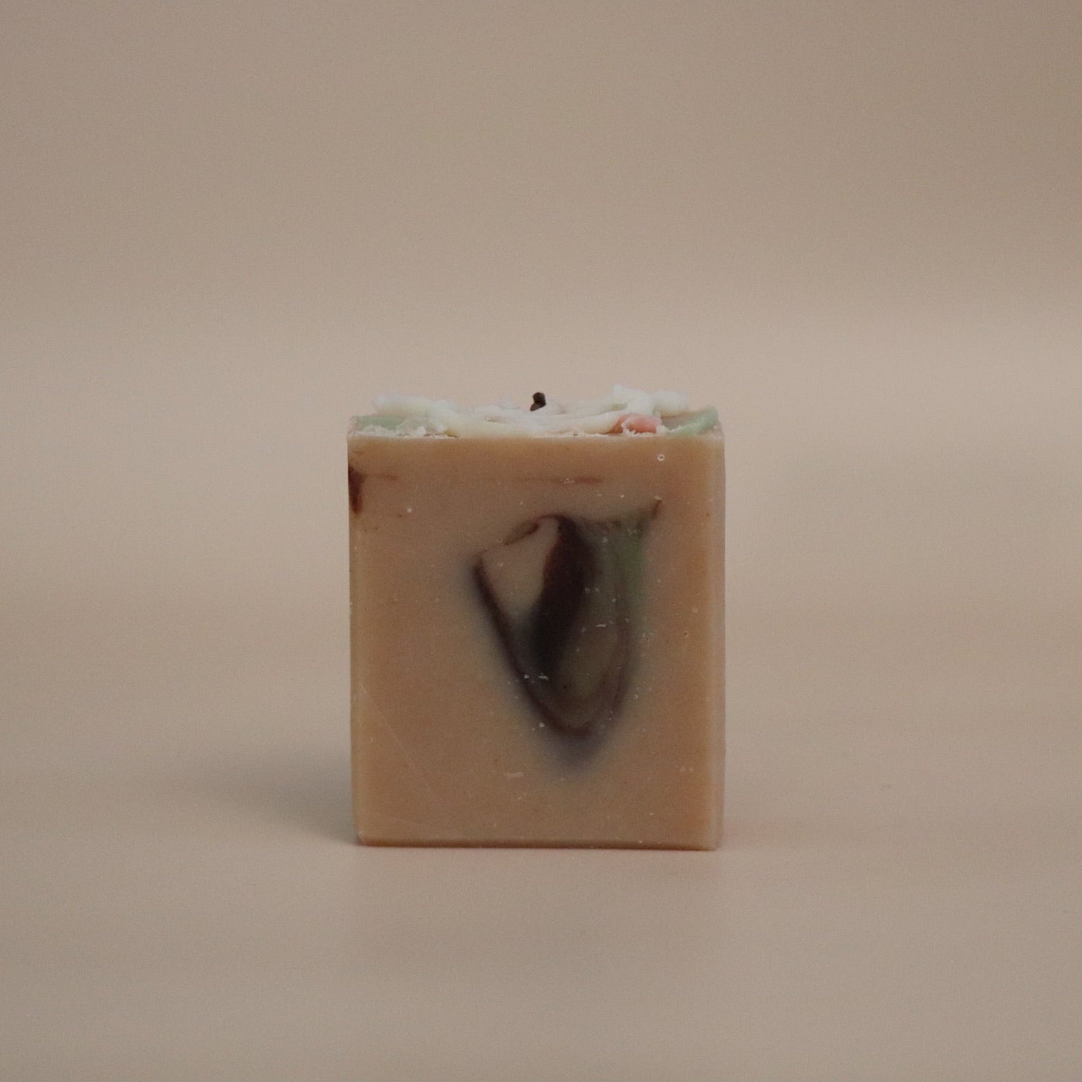 Square block of soap with a dark brown center on a beige background